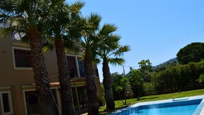 A swimming pool with palm trees and a building in the background. - Gold Luxury Villa Ialysos (Rhodes)
