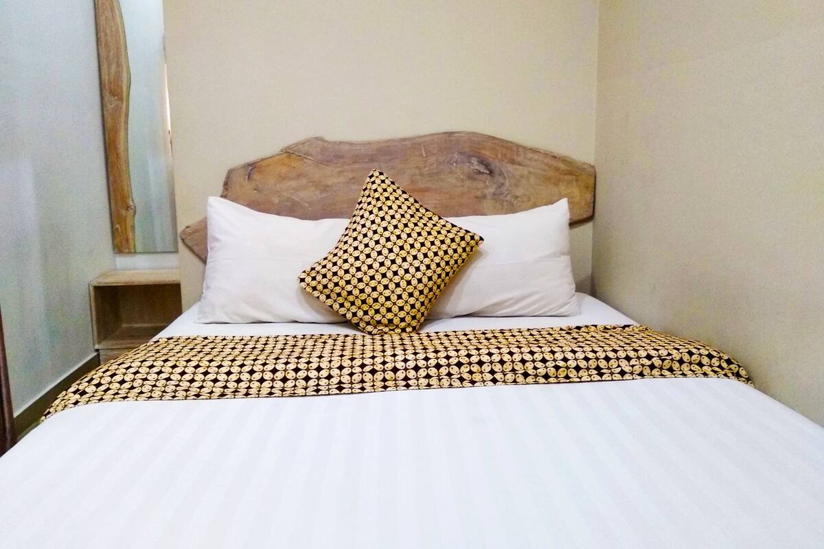 A neatly made bed with a patterned bedspread and two pillows, one with a circular design.