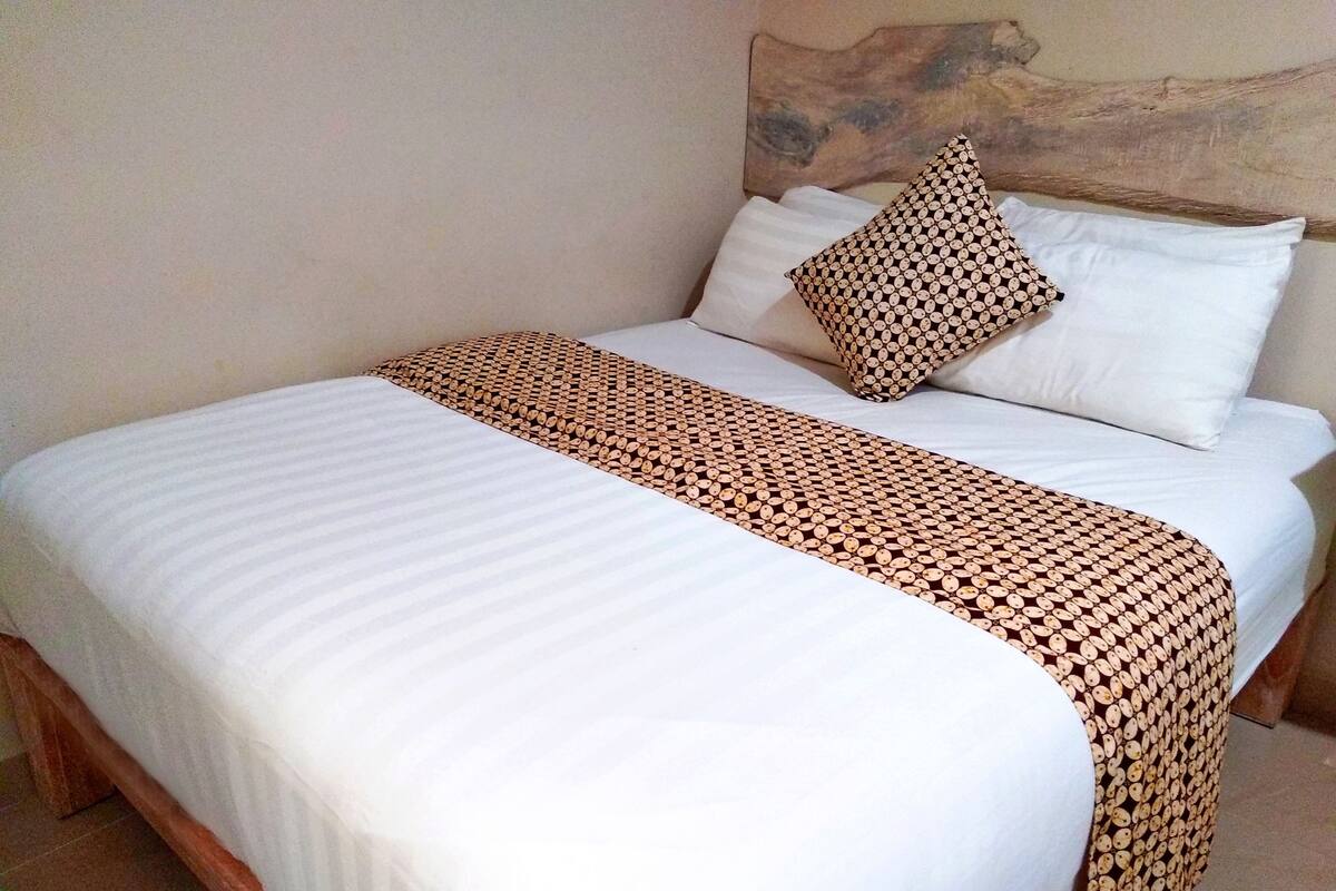 A neatly made bed with white bedding and a patterned throw blanket.