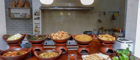 A buffet with various dishes and a kitchen in the background.