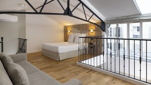 A modern bedroom with a balcony, wooden flooring, a bed, a sofa, and a staircase. - Yuna Blanche - Serviced Apartments (Paris)