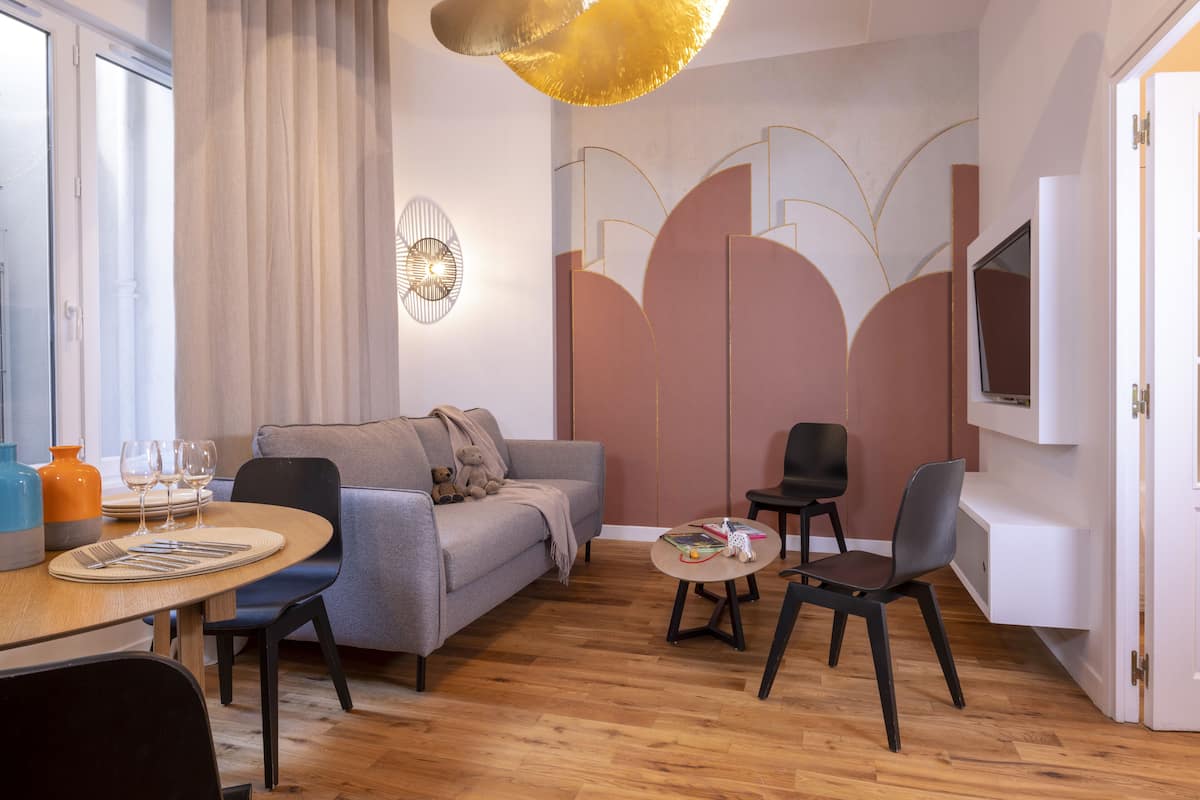 A modern living room with a grey sofa, a wooden dining table, and a small coffee table.