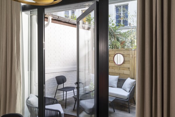 A glass door leading to an outdoor patio with a white brick wall, a wooden fence, and a round mirror on the wall.