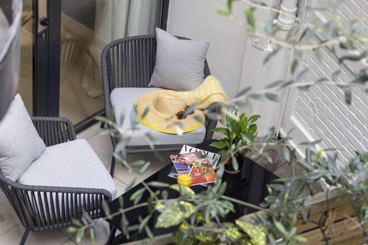 A balcony with two wicker chairs, a magazine, and a glass table.