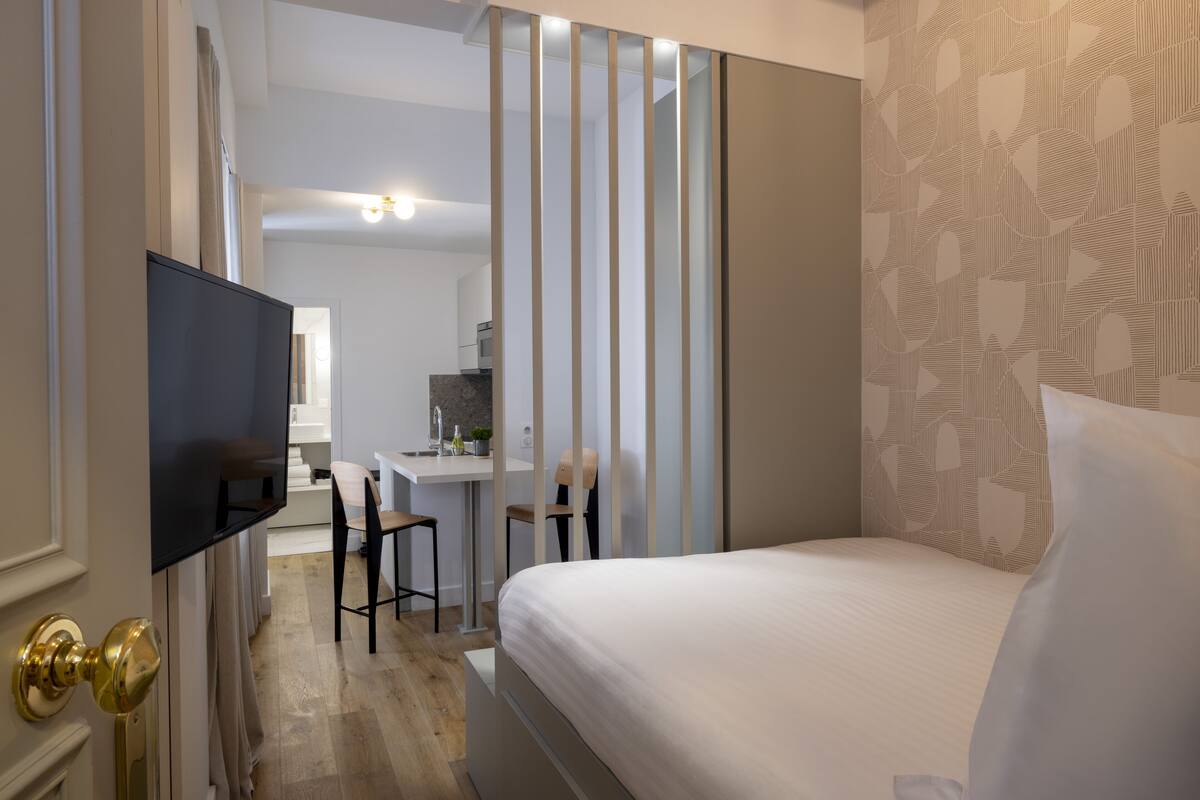 A modern hotel room with a bed, a desk, and a chair.