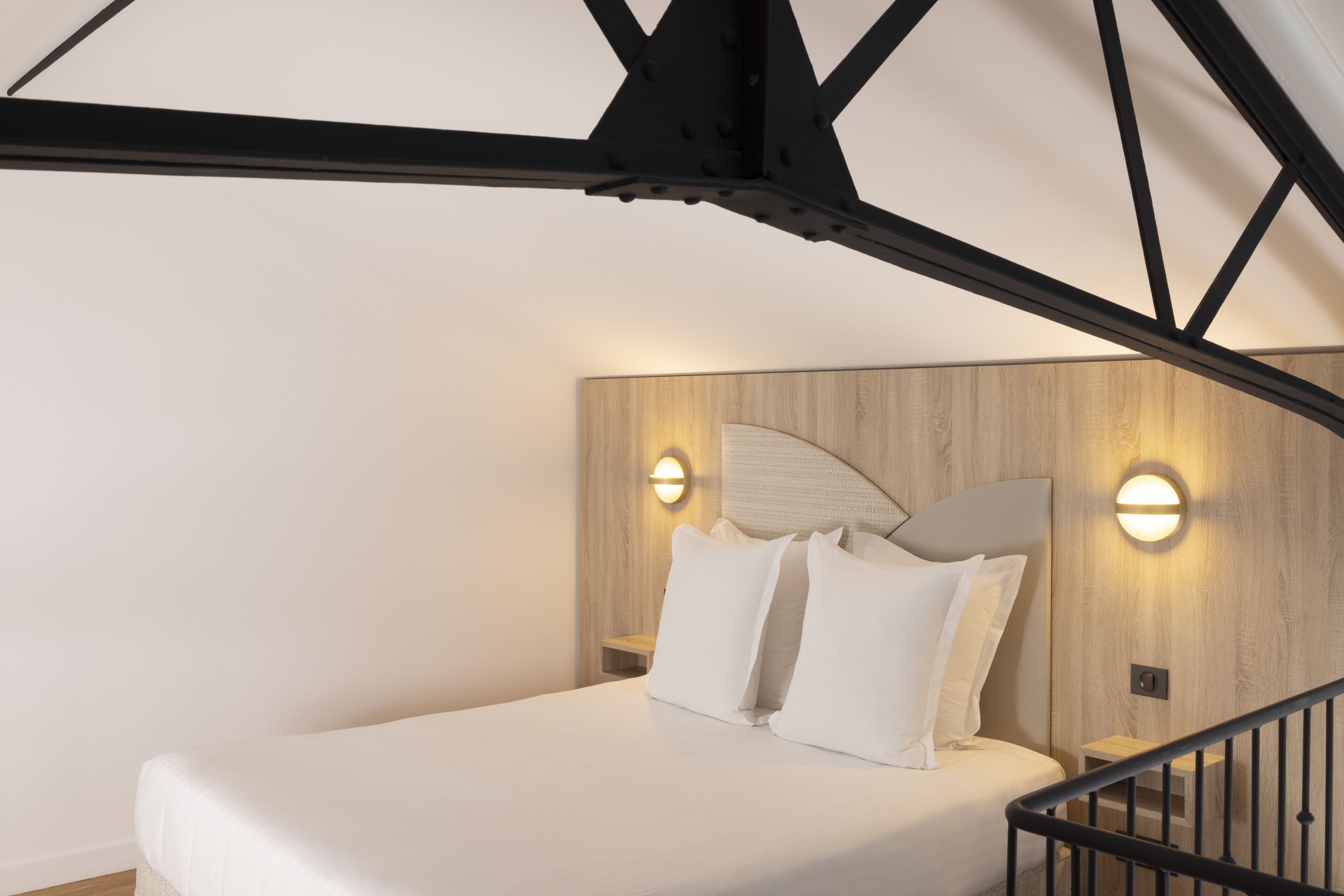 Ein modernes Schlafzimmer mit einem Bett, einem Holzkopfende und zwei Wandleuchten.