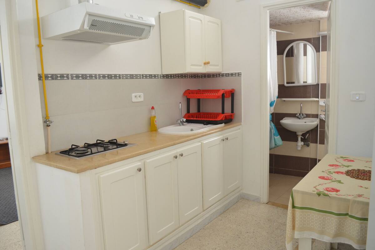 A compact kitchen with a gas stove, sink, and cabinets.