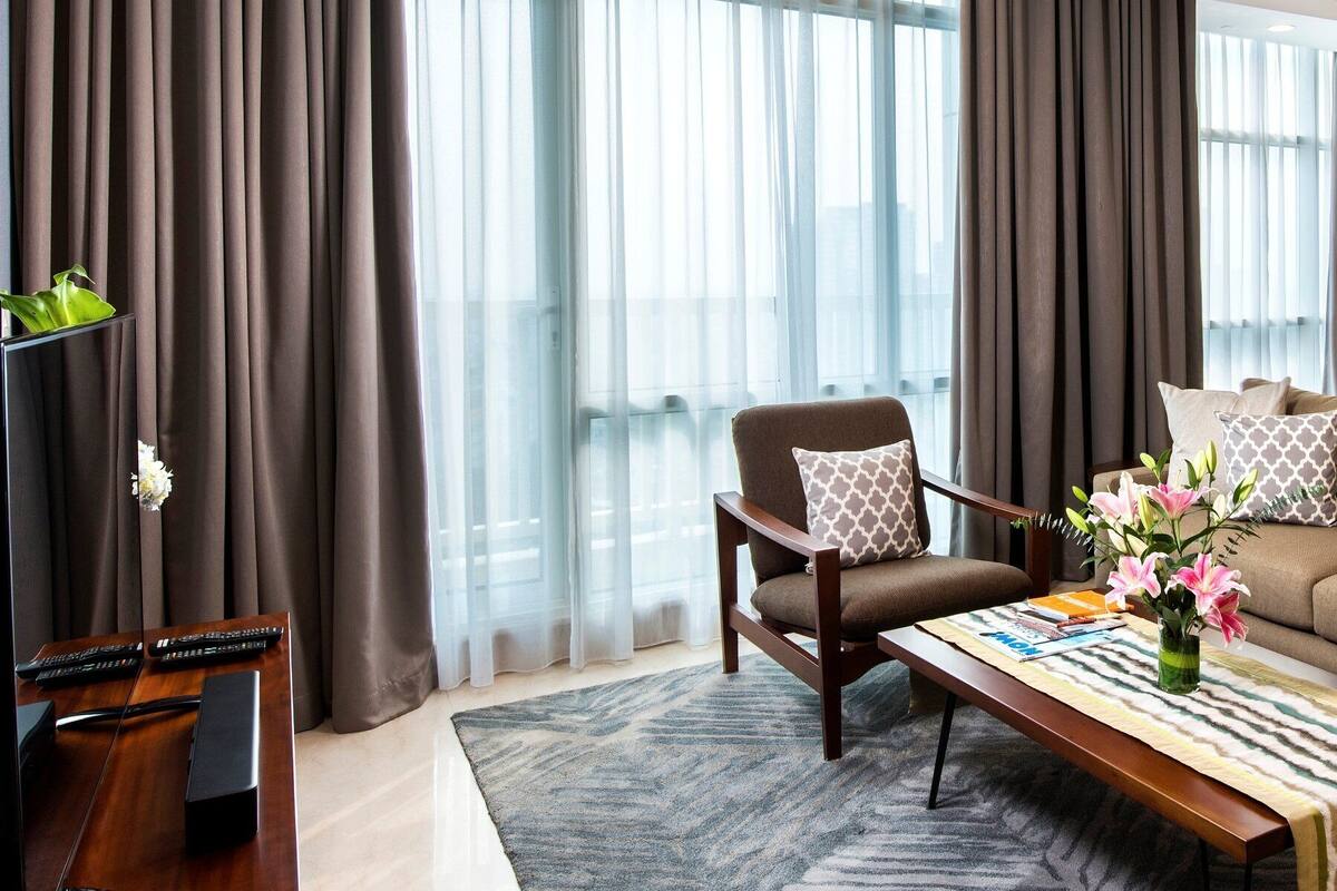 A modern living room with a sofa, armchairs, a coffee table, and a dining area with a table and chairs.