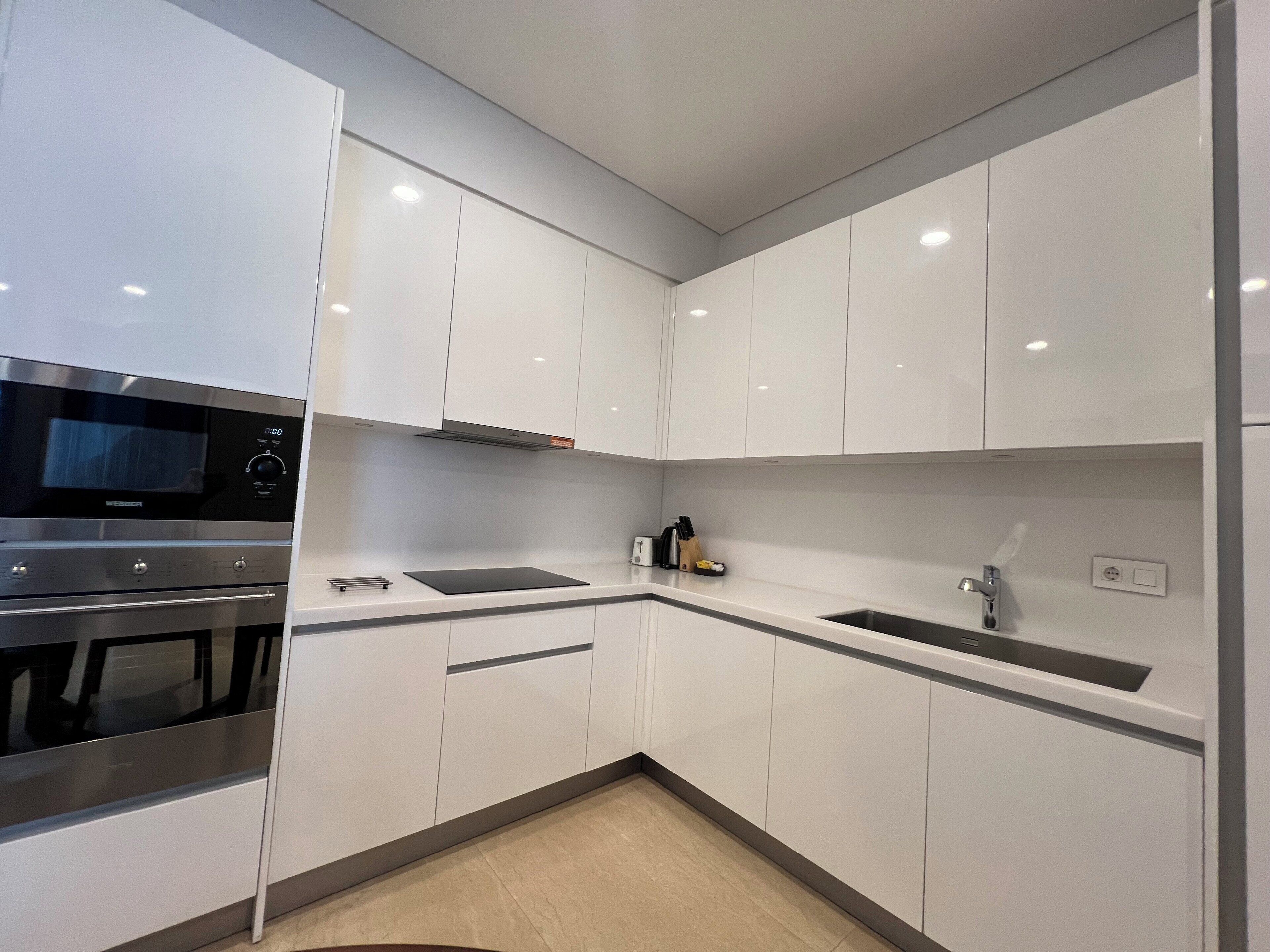 A modern kitchen with white cabinets, stainless steel appliances, and a black countertop.