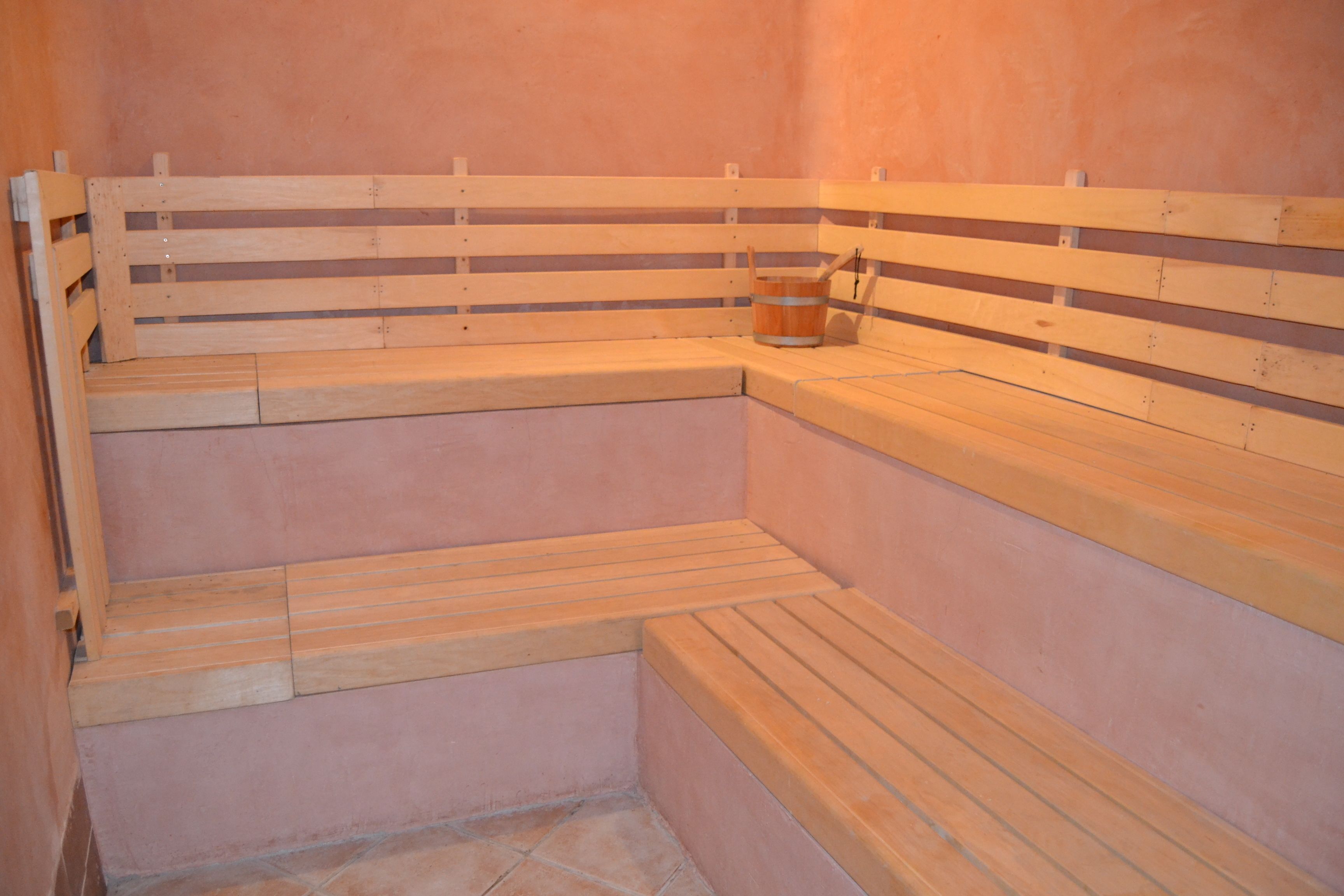 A sauna with wooden benches and a wooden bucket.