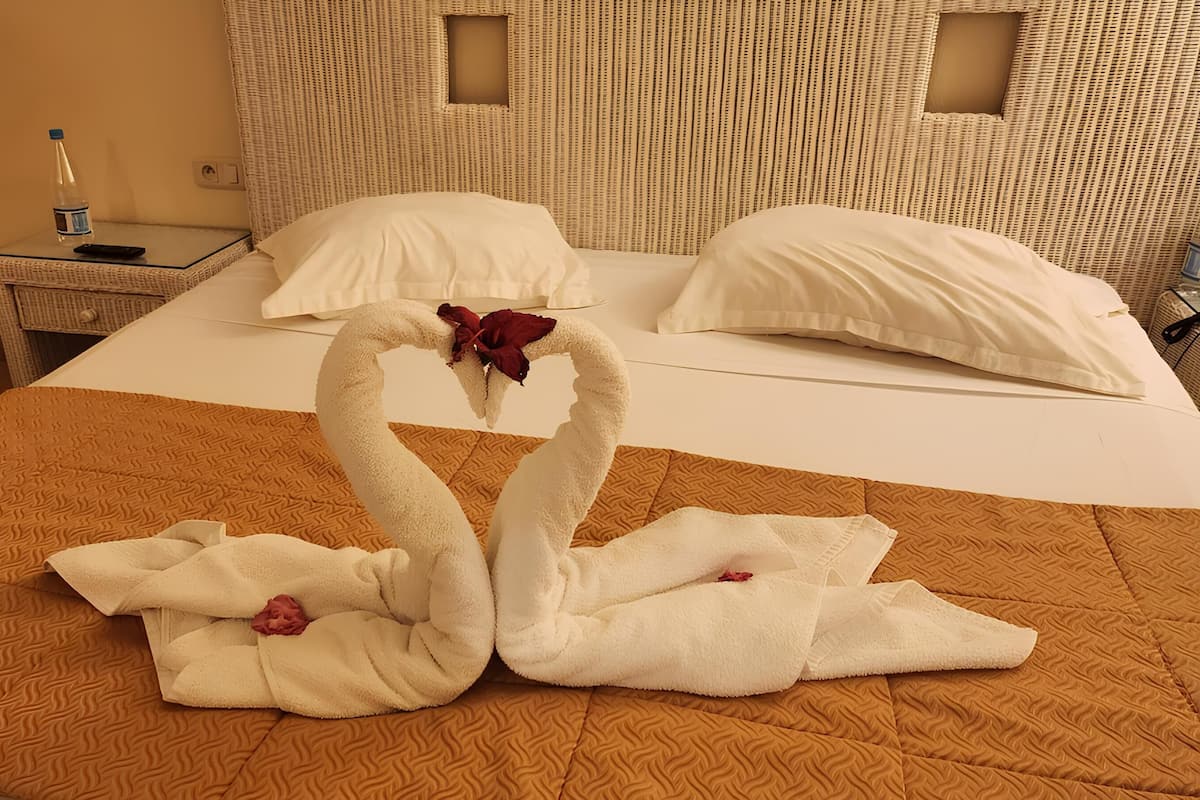 A hotel room with a bed, a nightstand with a lamp, and a suitcase.