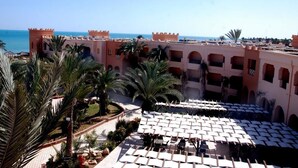 Une cour d’hôtel avec des espaces de repos en plein air et des palmiers.