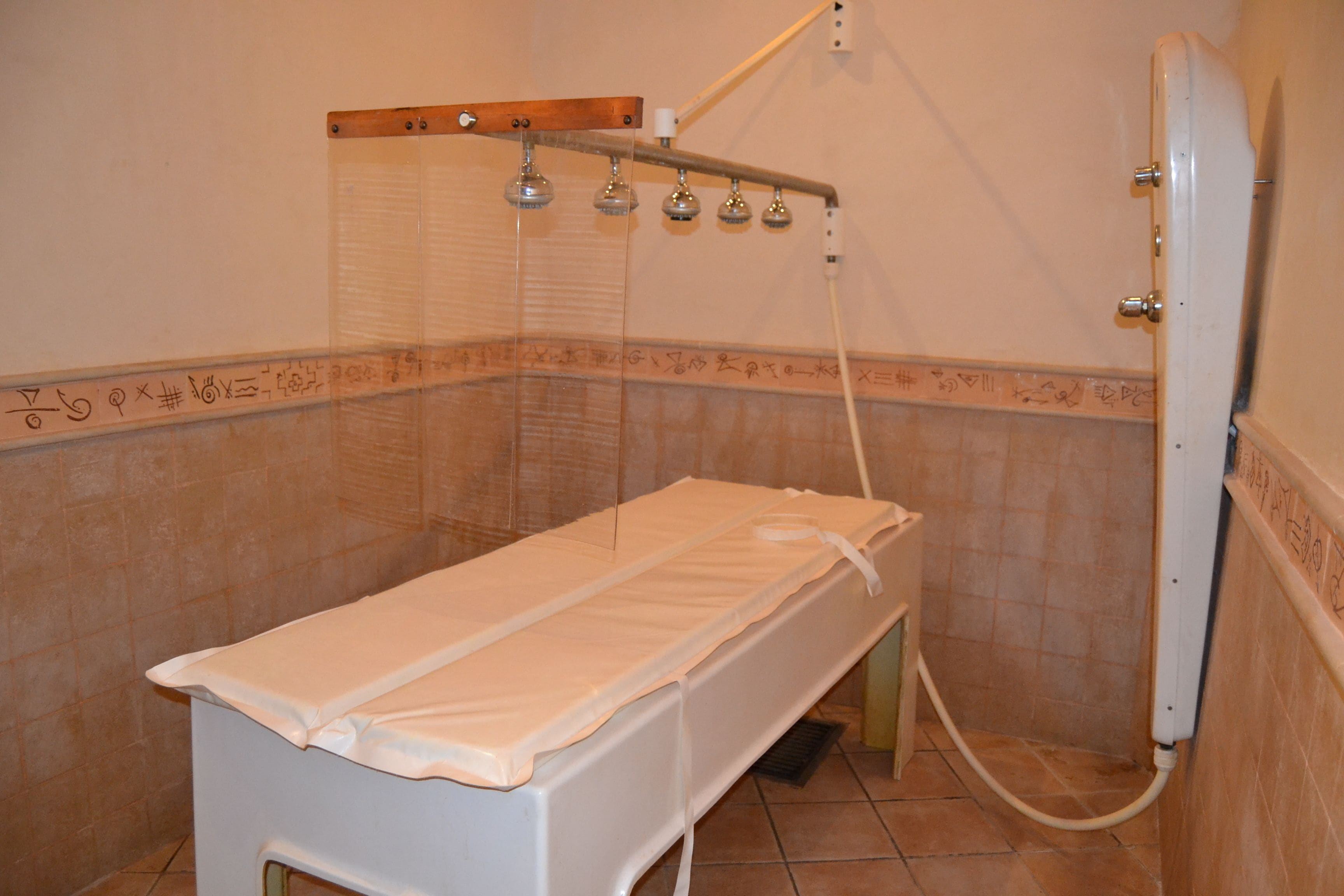A small, private room with a bed, a shower, and a tiled floor.