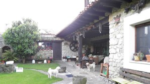A rustic stone building with a garden pathway, potted plants, and outdoor seating. - Casas Rurales El Terrero (Valdaliga)