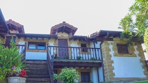 A traditional stone building with a wooden staircase leading to a balcony. - Casas Rurales El Terrero (Valdaliga)