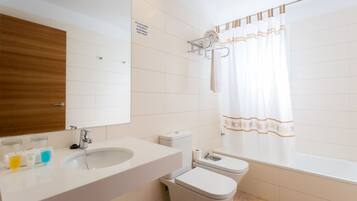 Un baño moderno con lavamanos, espejo, inodoro y bañera.