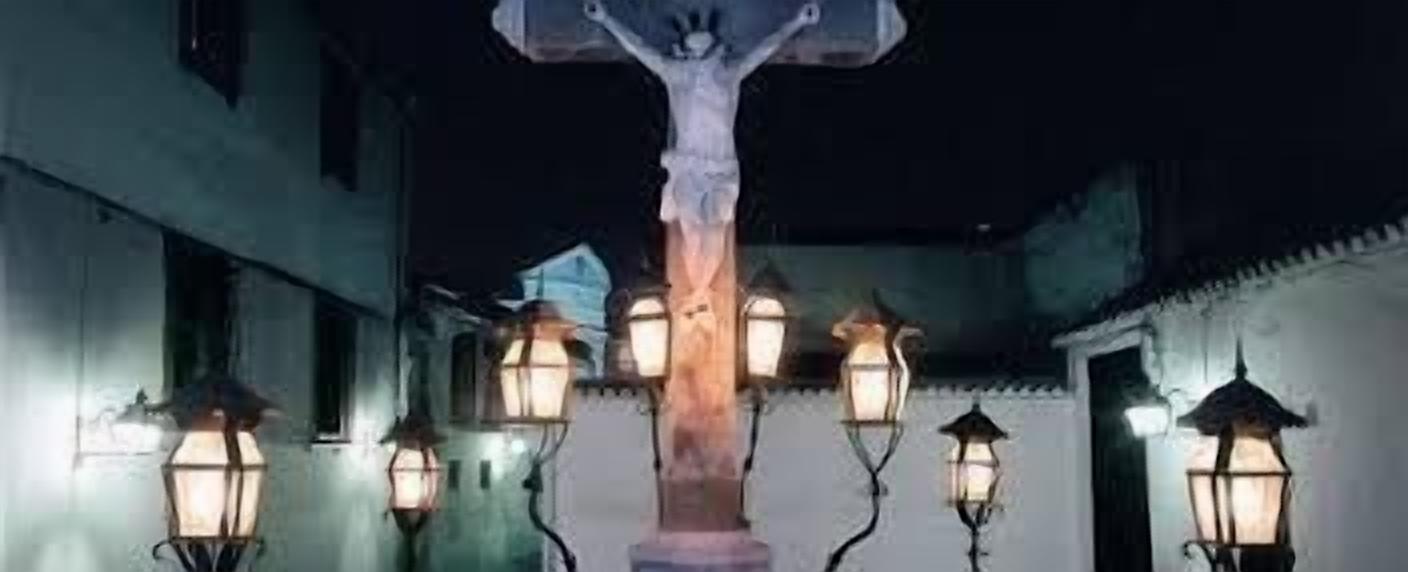 En smal gata med en centralt placerad, upplyst skulptur, omgiven av traditionella lyktor.