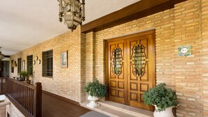A brick building with a wooden door, potted plants, and a staircase. - Hotel Riad Arruzafa (Córdoba)