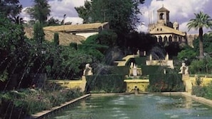 A garden with a fountain, statues, and a building with a dome. - Hotel Riad Arruzafa (Córdoba)