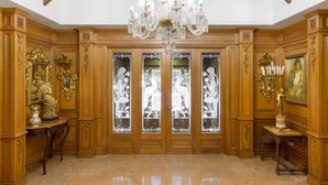 A spacious room with high ceilings, wooden paneling, a large chandelier, and a marble floor. - Hotel Riad Arruzafa (Córdoba)