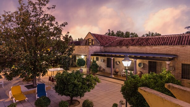 A courtyard with a brick building, outdoor seating, and potted plants. - Hotel Riad Arruzafa (Córdoba)