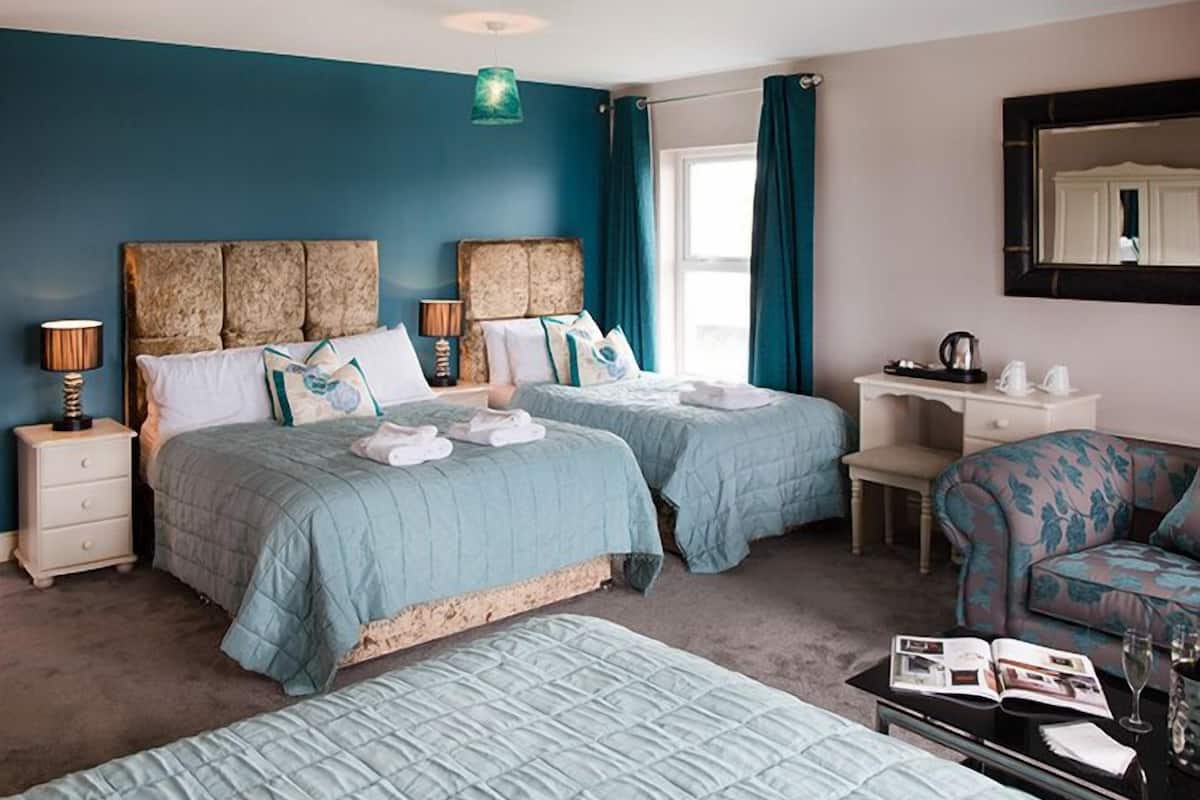 Une chambre d’hôtel avec deux lits, un bureau, une chaise et un grand miroir.