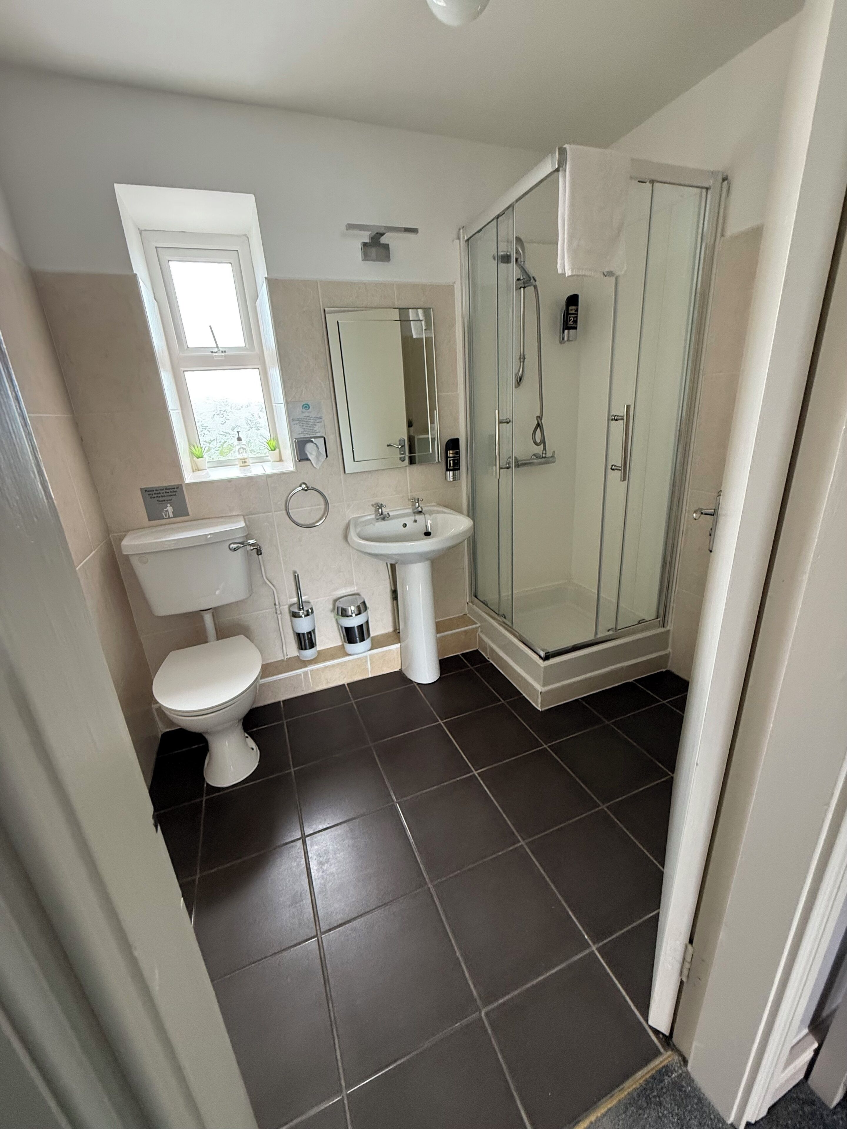 Une salle de bain moderne équipée de toilettes, d’un lavabo et d’une douche à parois de verre.