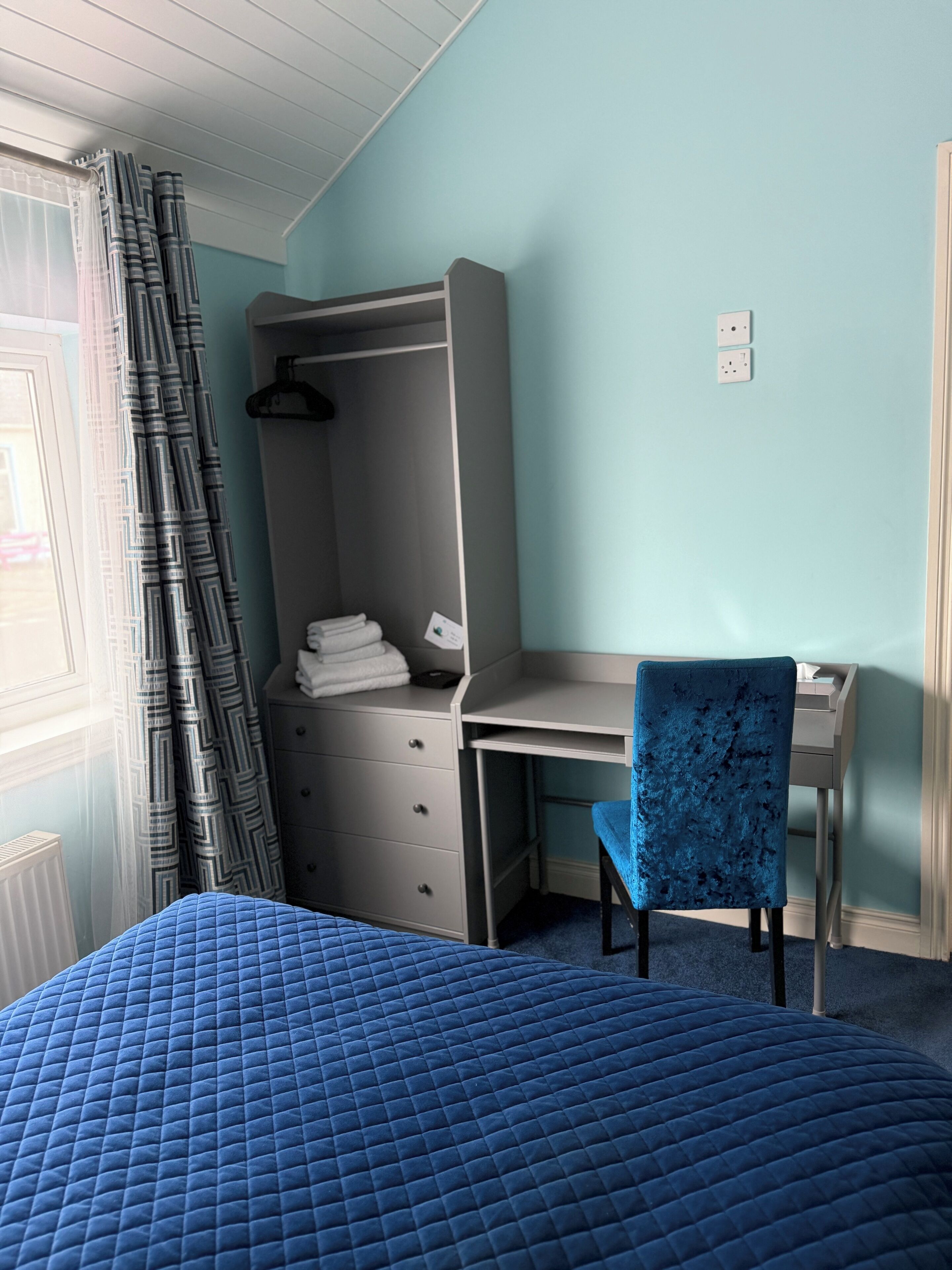 Un dormitorio con cama, escritorio, silla y armario.