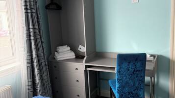 Un dormitorio con cama, escritorio, silla y armario.