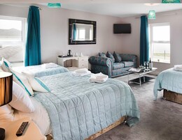 Habitación de hotel con dos camas, un sofá, un escritorio, un televisor y vistas al exterior.