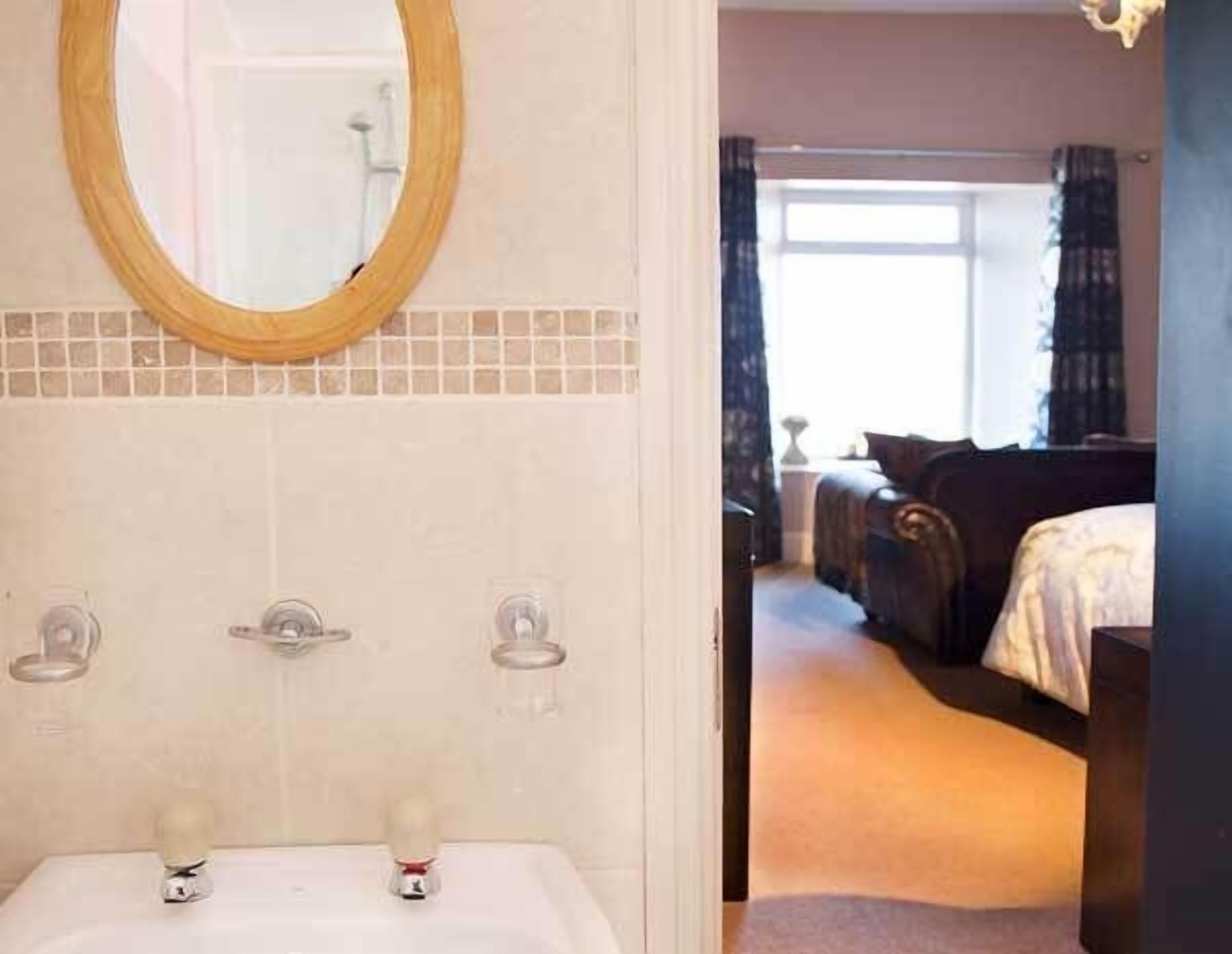 Une salle de bain équipée d’un lavabo, d’un miroir et de deux distributeurs de serviettes.