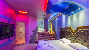 Una camera d'albergo moderna con un grande letto, una TV a schermo piatto e un design di soffitto originale.
