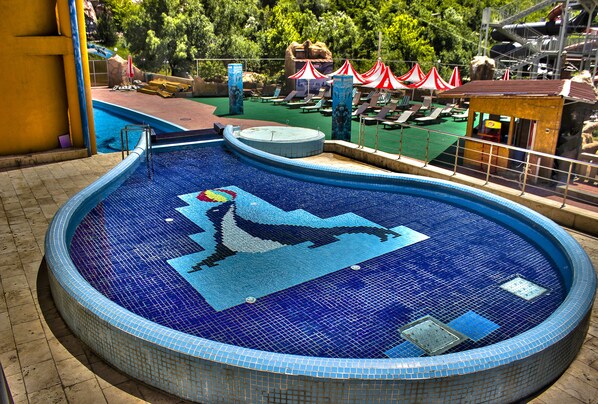 A swimming pool with a dolphin mosaic, sun loungers, and a small pavilion. - Aquapark Hotel & Villas (Yerevan)