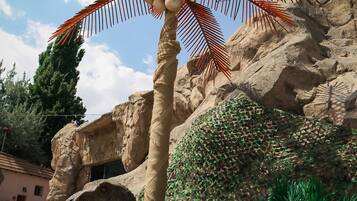 Um modelo de dinossauro com uma palmeira em frente a um fundo rochoso.