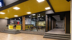 Un interior modern amb un sostre groc, grans finestres i una escala que condueix a un pis superior.