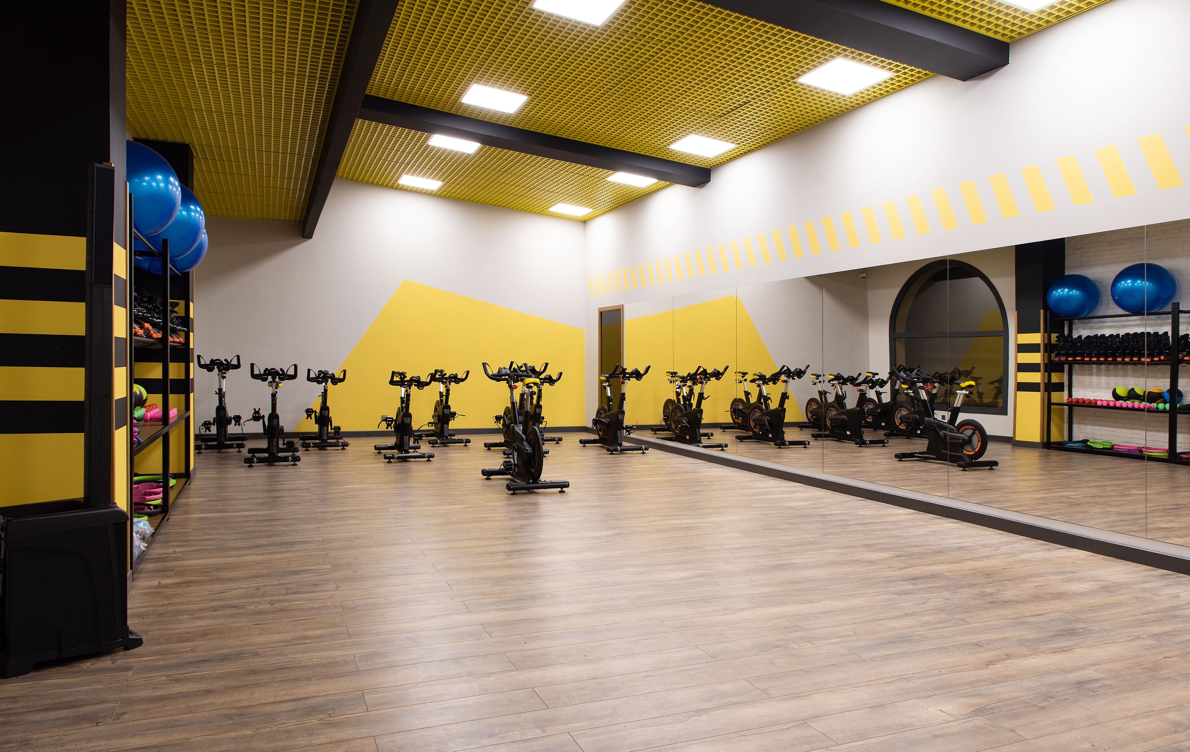Een sportschool met hometrainers, spiegels en trainingsballen.