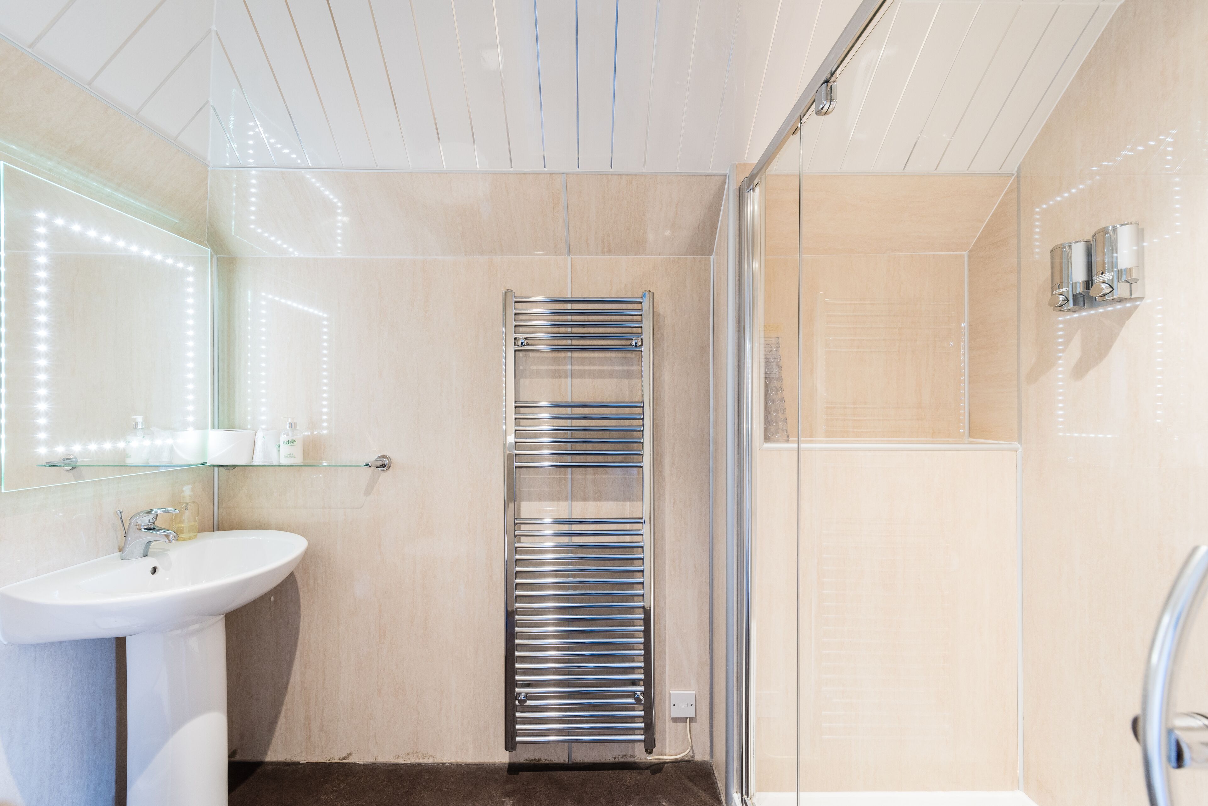 Ein modernes Badezimmer mit Duschkabine aus Glas, integriertem Waschbecken und Handtuchhalter.