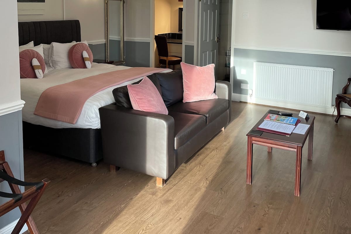 Un dormitorio moderno con cama, sofá, mesa de centro y televisor.