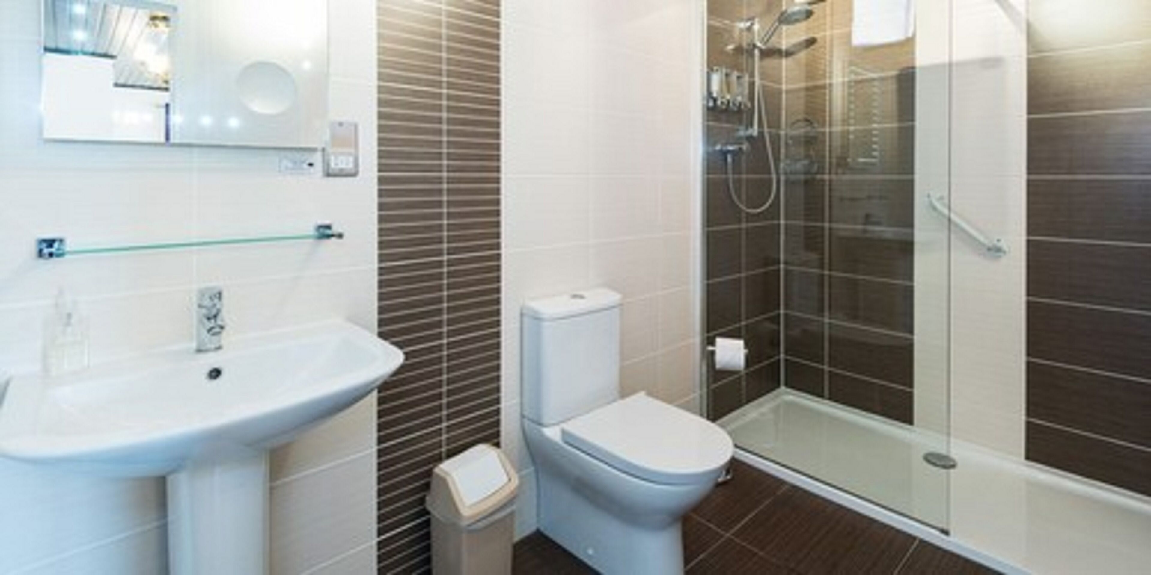 Un baño moderno con lavabo, inodoro y cabina de ducha de vidrio.