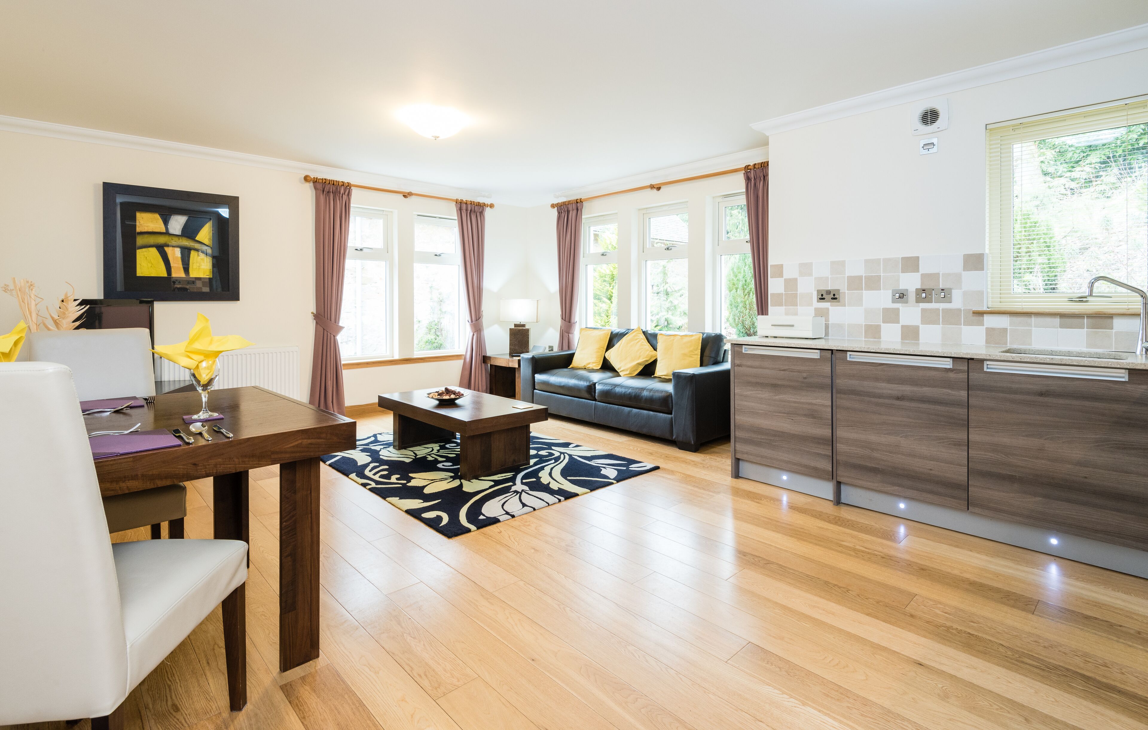 A modern living room with a sofa, dining table, and kitchen area.