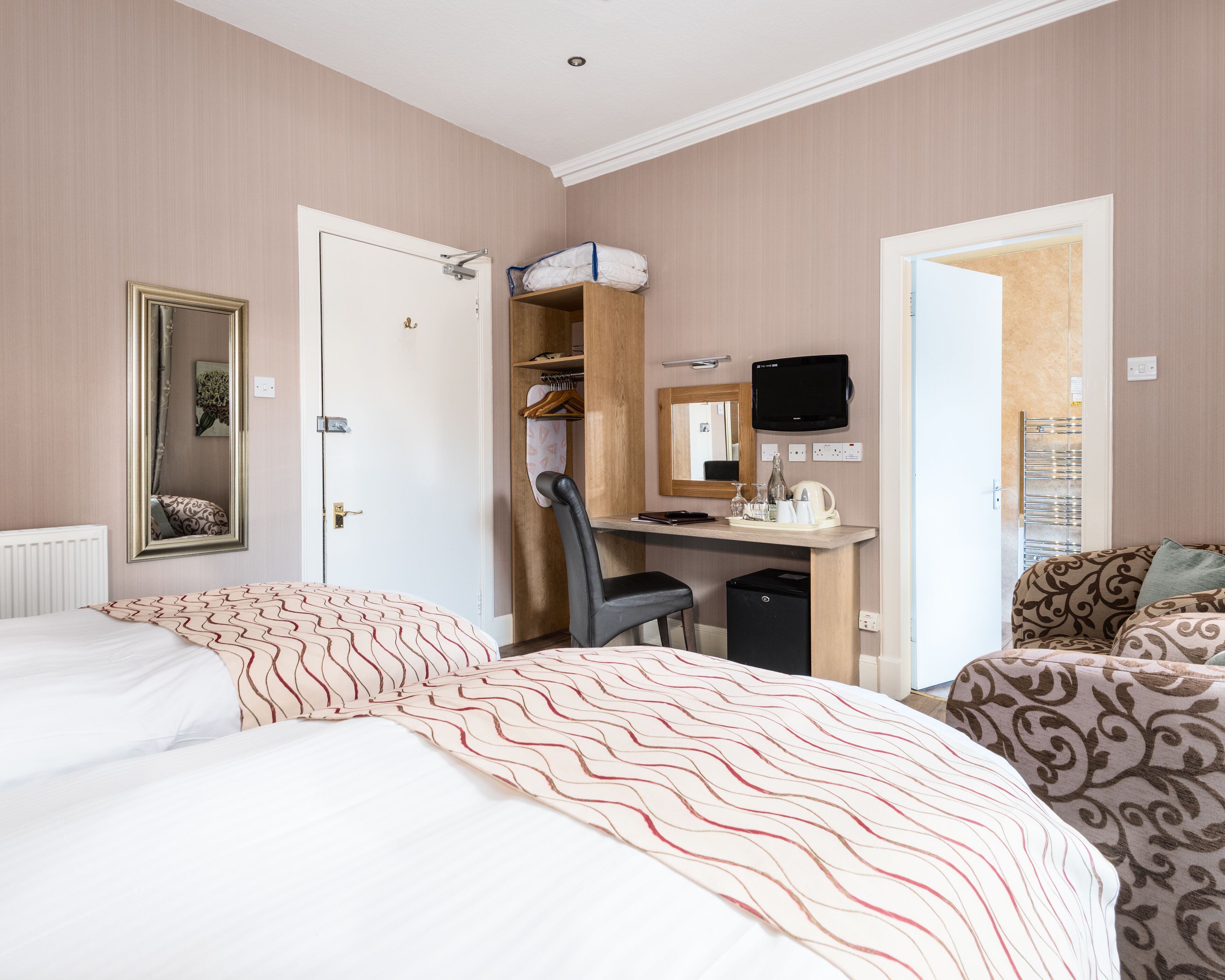 Une chambre d’hôtel comprenant un lit, un bureau avec une chaise, une télévision et une armoire.