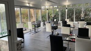 Un'ampia sala da pranzo interna con grandi finestre, arredi moderni e vista sul giardino.