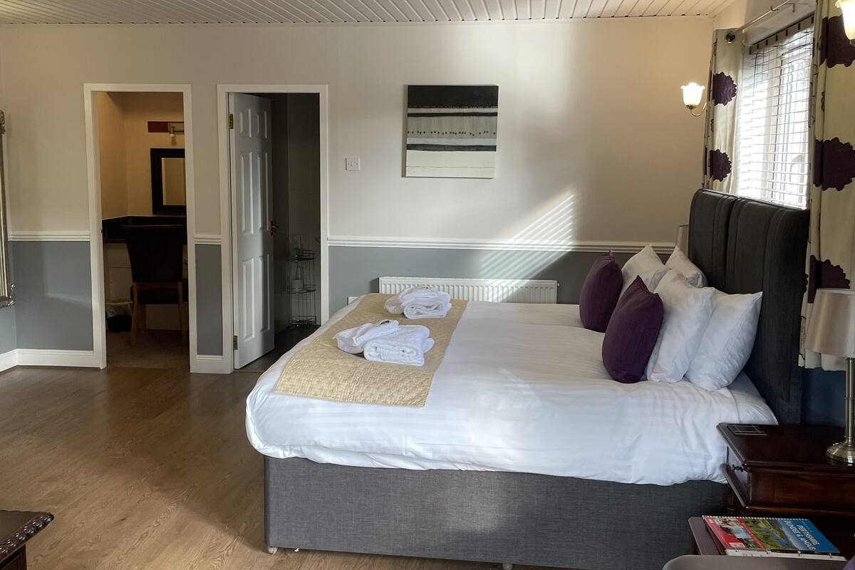 Una habitación de hotel con una cama, una mesita de noche, una lámpara, una silla y vistas al pasillo.