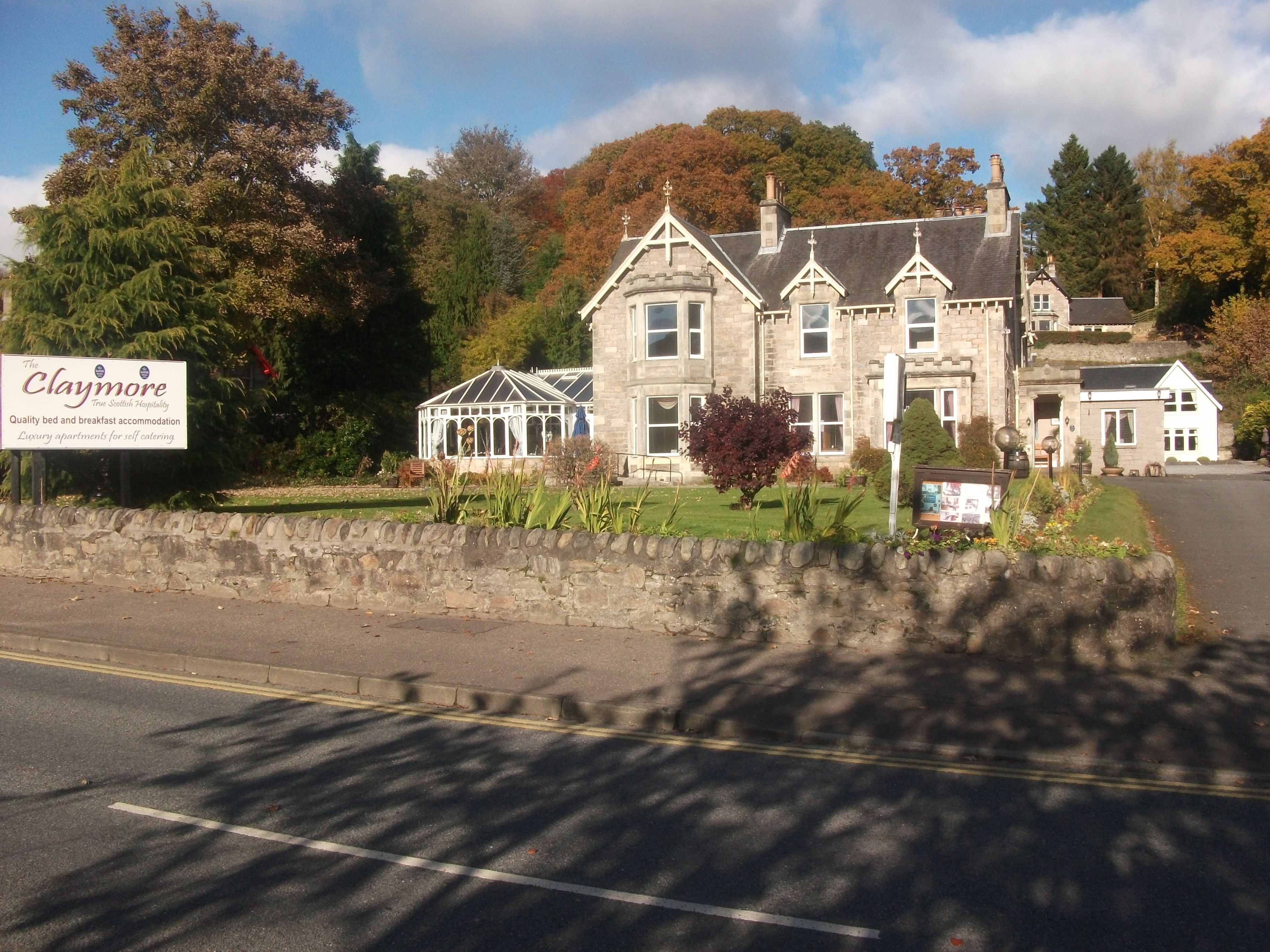 A large, historic stone building with multiple windows and a conservatory.