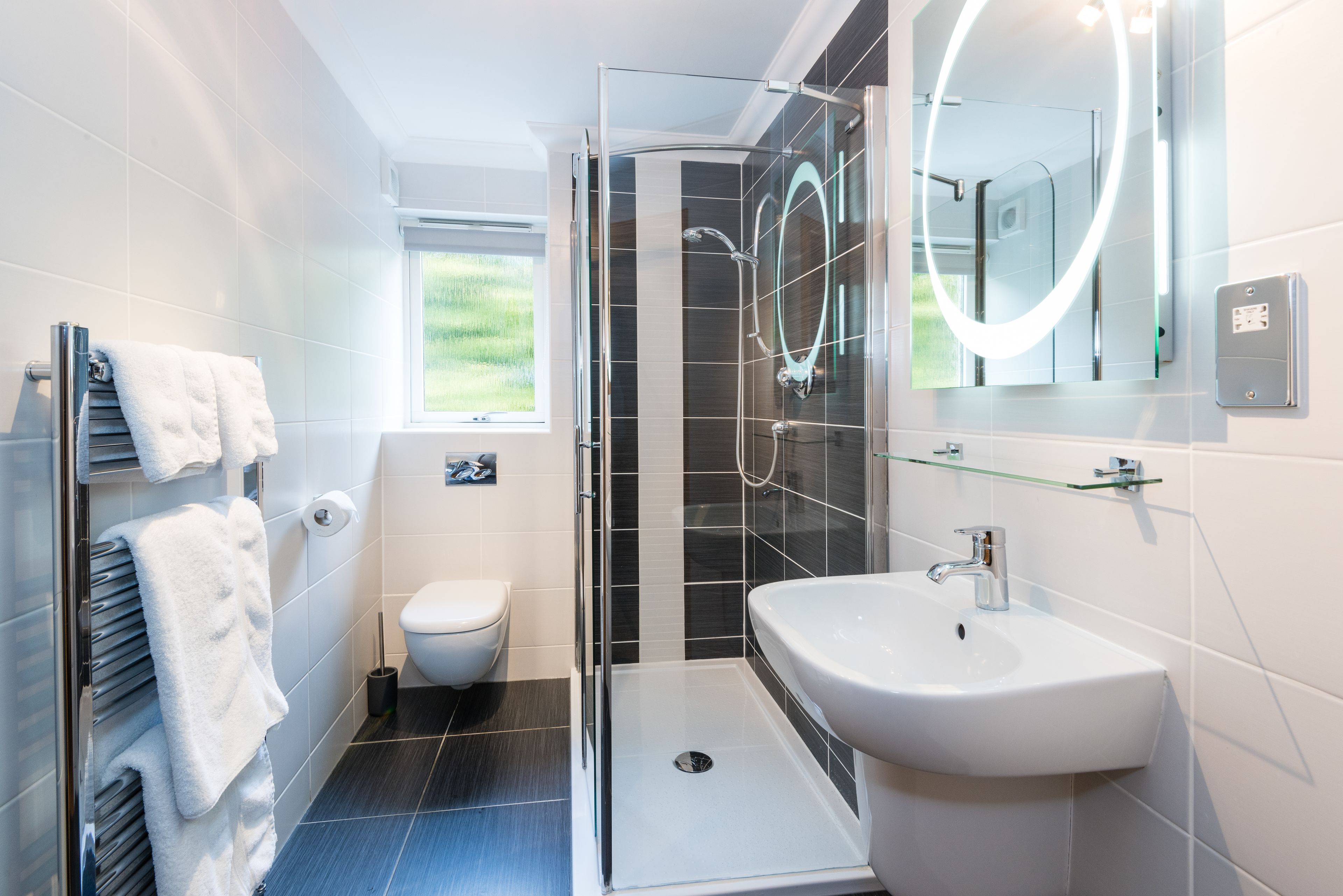 Ein modernes Badezimmer mit einer Duschkabine, einem weißen Waschbecken und einer Toilette.