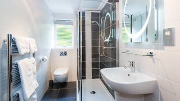 A modern bathroom with a glass-enclosed shower, a white sink, and a toilet.