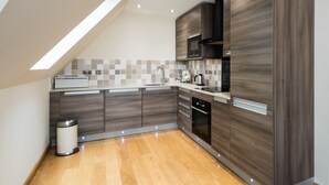 Una cucina moderna con mobili in legno, forno a incasso e finestra sul tetto.
