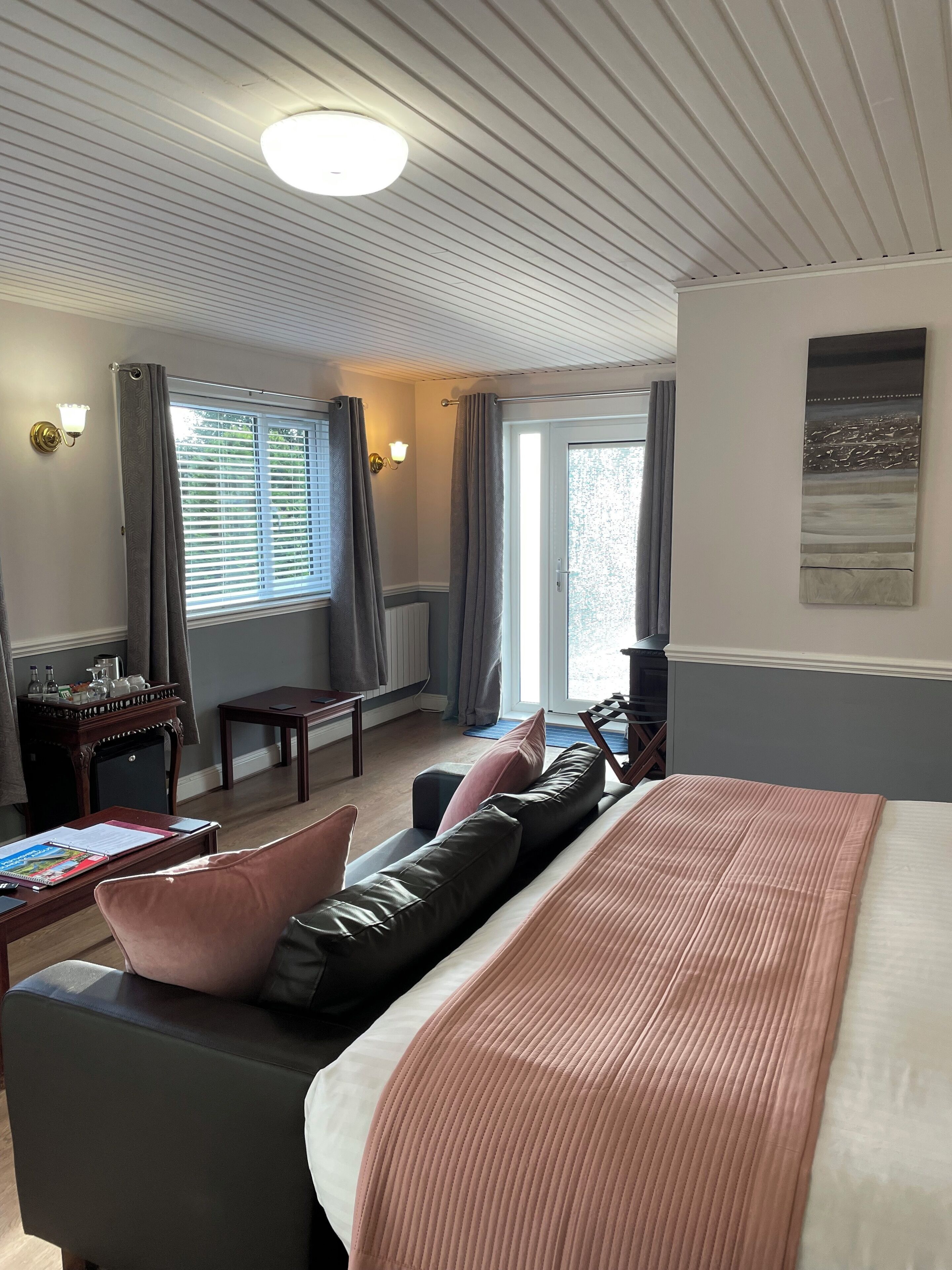 A hotel room with a bed, a desk, a chair, and a view of the outdoors through a window.