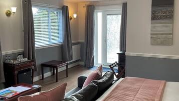 A hotel room with a bed, a desk, a chair, and a view of the outdoors through a window.