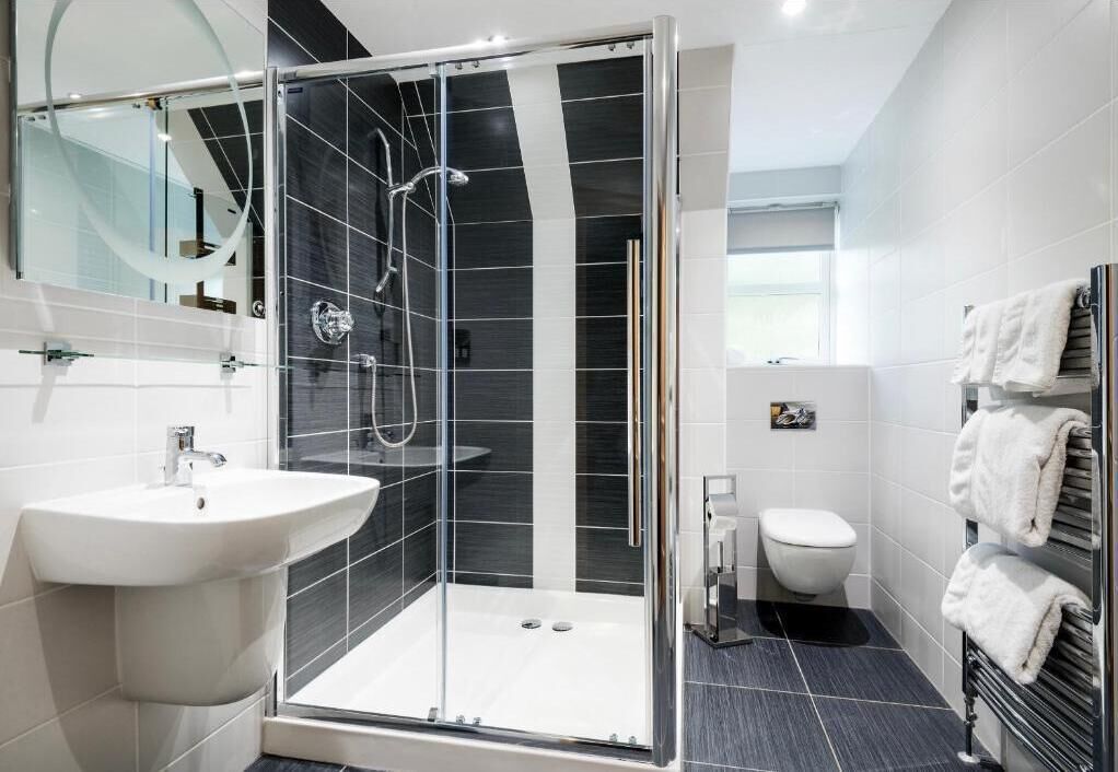 Ein modernes Badezimmer mit einer Duschkabine aus Glas, einem weißen Waschbecken und einer Toilette.